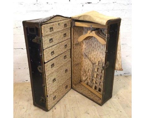 A 1920's steamer trunk wardrobe the rivetted metal bound trunk with domed top and leather carrying handle opening to reveal i
