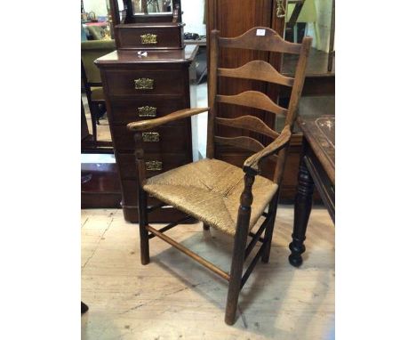 A 19thc elm ladder back open arm chair the ladderbacks with arched centres on curved arms on turned supports over rush seats 