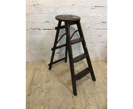 A first half 20thc elm folding step ladder with circular top with pierced handle over three graduated rungs, (when open 85cm 