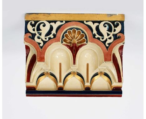 A large Craven Dunnill architectural tile, modelled in relief with foliage panels above arches, glazed in colours and gilt on