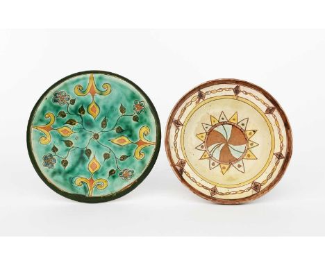 A Della Robbia Pottery plate by A, painted with radiating flower stems in green and blue on a turquoise ground, the rim with 