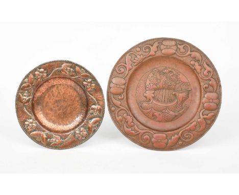 A John Pearson repousse copper plate, dated 1905, the rim hammered in relief with a frieze of flowers and foliage, another la