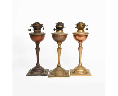 Three patinated copper and brass oil lamps designed by WAS Benson, each on square base with domed foot, shouldered, flaring c