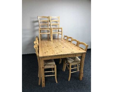 A rectangular pine dining table and ten ladder backed chairs 