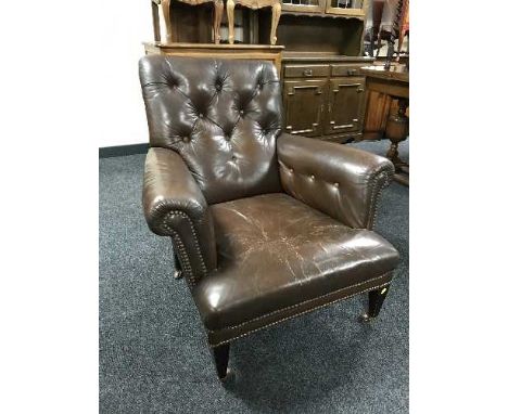 An early 20th century brown button leather armchair 