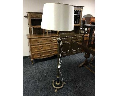 A black and gilt standard lamp on paw feet 