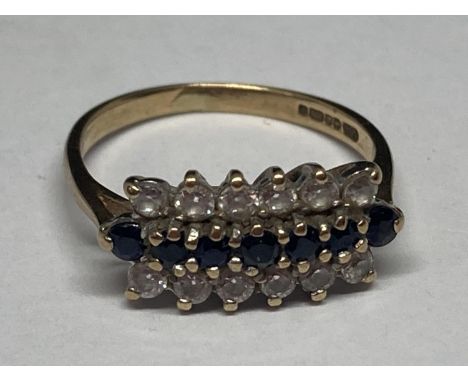 A 9 CARAT GOLD RING WITH SEVEN IN LINE SAPPHIRES SURROUNDED BY TWELVE CUBIC ZIRCONIAS SIZE L 