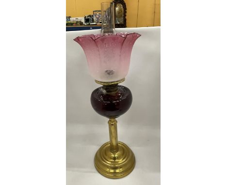 AN EARLY TO MID 20TH CENTURY BRASS CORINTHIAN COLUMN OIL LAMP WITH CRANBERRY GLASS SHADE 
