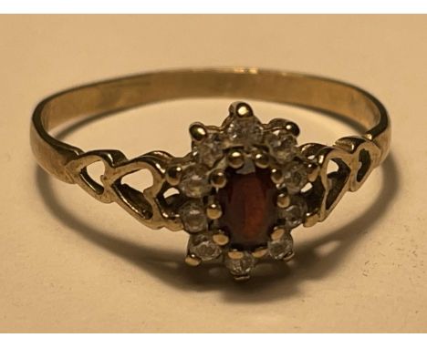 A 9 CARAT GOLD RING WITH CENTRE GARNET SURROUNDED BY TEN CUBIC ZIRCONIAS SIZE O/P 