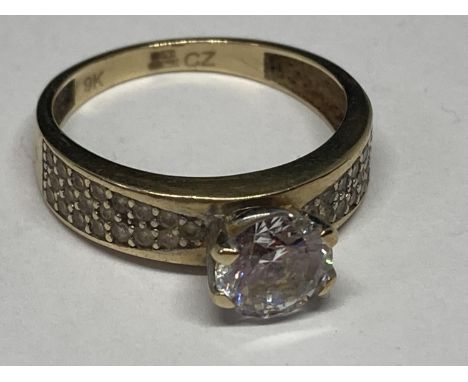 A 9 CARAT GOLD RING WITH CENTRAL CUBIC ZIRCONIAS AND CHIPS TO THE SHOULDERS SIZE N 