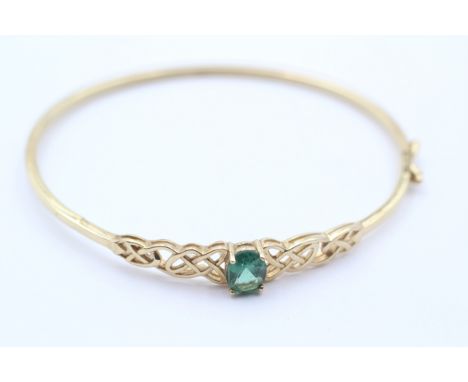 A 9ct gold and green stone twist opening bangle, internal 60 x 52mm, 4.6gm 