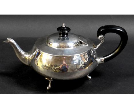 An Arts & Crafts silver teapot, of compressed ovoid form, with all over hammered finish, ebonised finial and handle, raised o