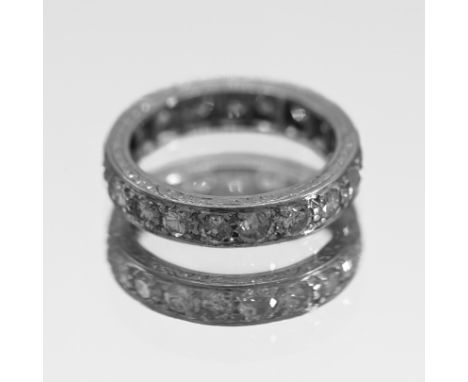 A full band eternity ring, probably platinum, classic stud-claw set with engraved border, size K, one stone damaged, with 19 