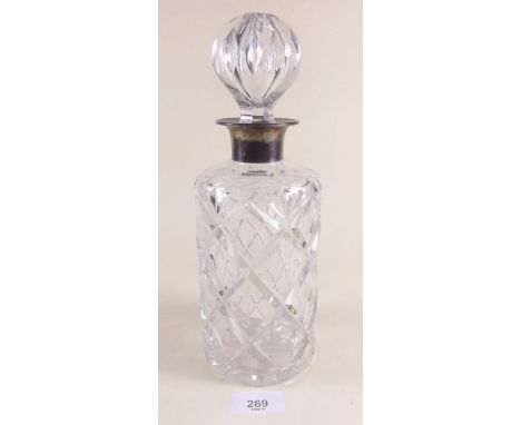 A cut glass decanter with silver collar