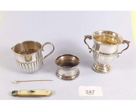 A small group of silver items including miniature trophy cup, cream jug, napkin ring, gold stick pin etc