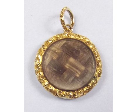 A Victorian gold circular hair locket with decorated border and engine turned back, not marked but tested gold