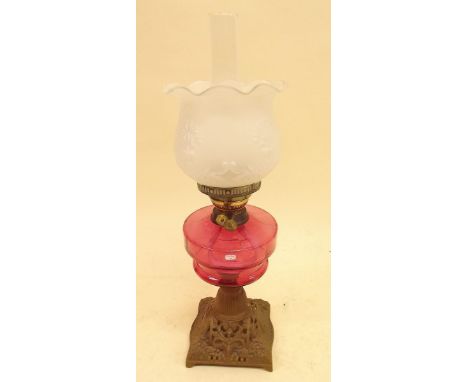 A Victorian oil lamp with cranberry reservoir and opaque fitted glass shade