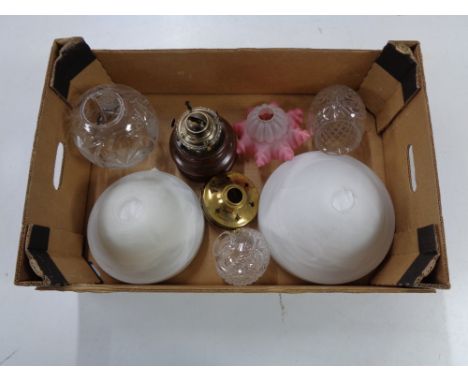 A tray of glass light and lamp shades together with an oil lamp base 