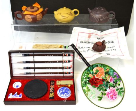 An Oriental collector's lot comprising three boxed Yixin purple clay teapots, a boxed clay tea-toy, an Oriental wooden cased 