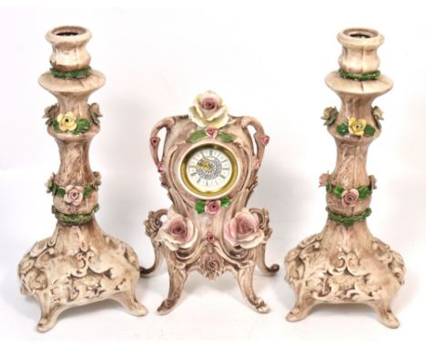 A Capodimonte mantel clock with relief rose decoration, the dial set with Roman numerals, height 26cm and a pair of candlesti
