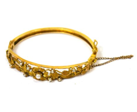A yellow metal bangle with floral and foliate design to the top, set with small seed pearls, approx 15.1g.