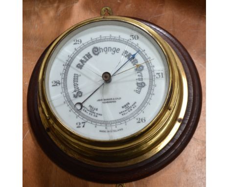 An early 20th century brass ship's barometer with white enamel dial inscribed 'John Barker & Co Ltd, Kensington', mounted on 