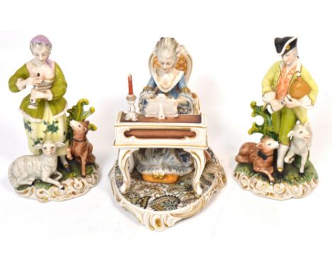 A 20th century figure group of a seated lady playing a piano and a pair of Dresden figures each with lambs at their feet and 