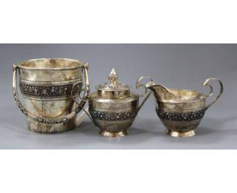 Three items of Burmese 900 white metal by Paung, including an ice bucket, a cream jug with scrolled strap handle and a matchi