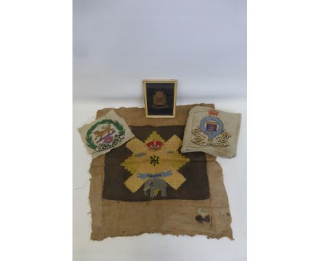 A framed and glazed bullion wire Wiltshire Regiment badge with three embroidered badges of the Hampshire Regiment, the Royal 