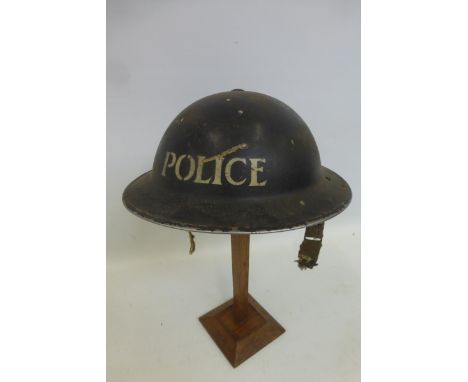 A WW2 Police helmet with liner and damaged chin strap.