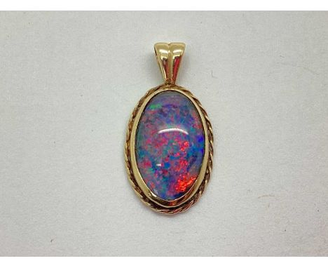 A 9ct Gold Opal Doublet (?) Pendant, the oval stone collet set between ropetwist surround and flared surmount.