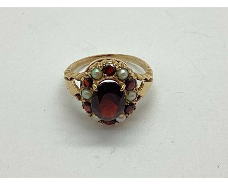 A Vintage Garnet and Seed Pearl Dress Ring, of cluster design, the oval centre stone four claw set within collet set surround