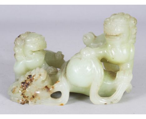 A CHINESE CELADON JADE MODEL OF TWO BUDDHISTIC LIONS AND A PUP, playing with a brocaded ball, 5.9in wide & 4in high.