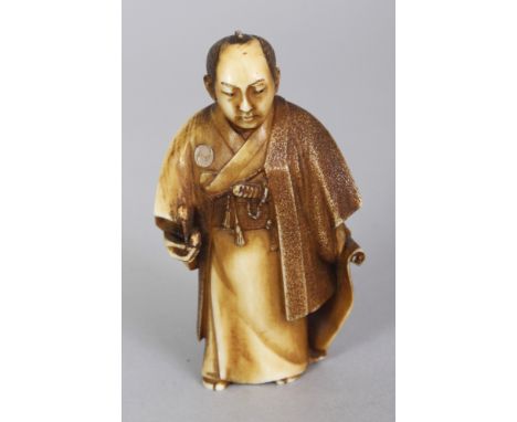 A GOOD QUALITY SIGNED JAPANESE MEIJI PERIOD MOTHER-OF-PEARL INLAID STAINED IVORY NETSUKE OF A STANDING SAMURAI, the base with