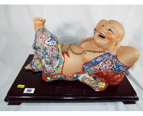 A large hand-painted ceramic Buddha on a wooden plinth 26 cm (h) x 46 cm (w)