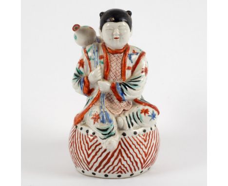 A Japanese kakiemon water dropper, circa 1680, modelled as a boy sitting on a drum and with gourd slung over his shoulder, 14