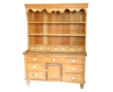 A Victorian stripped pine kitchen dresser, with plate rack top having seven spice drawers with ceramic knob handles, and an a