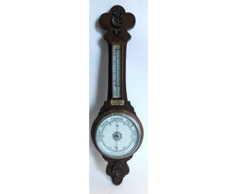 An early 20thC carved oak wheel barometer, with ceramic dial and thermometer, presentation plaque, Presented to Mr W Ashford 
