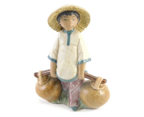 A Lladro ceramic figure of an Oriental child carrying water, 19cm high.