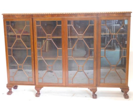 An early 20thC flame mahogany breakfront bookcase, in the Chippendale manner, with gadrooned top, four astragal glazed doors,