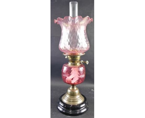 A 20thC oil lamp, with clear glass funnel, amethyst coloured glass ribbed shade, cranberry style reservoir, on circular socle