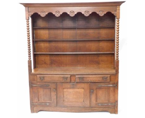 A 19thC Arts and Crafts dresser, with plate rack top, having rose carved frieze, bobbin turned supports, boarded plate rack, 
