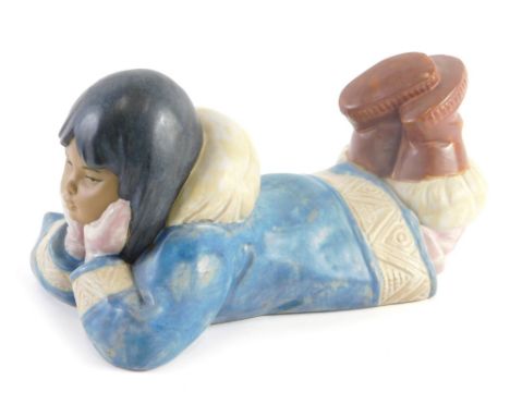 A Nao porcelain figure, of a young Eskimo girl laying on her front, mottled glaze.