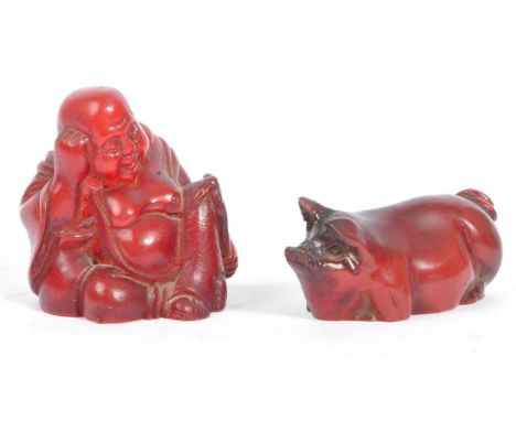 Two 20th century Japanese resin netsuke figures. The netsuke figures depicting a pig in a sitting position, and a sleeping bu