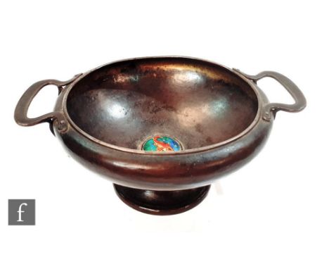 An Arts &amp; Crafts twin handled pedestal bowl of plain form with a central enamel roundel of a goldfish to the centre, heig