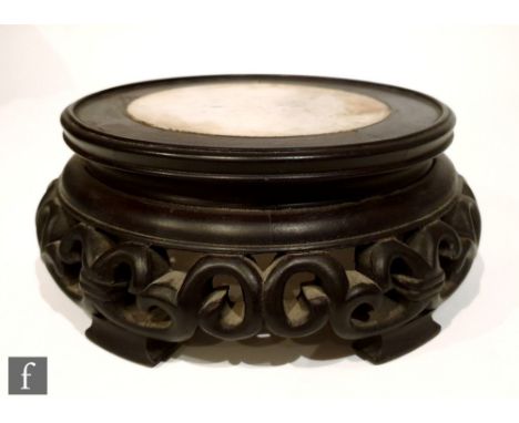 A Chinese hardwood stand of circular form, with an inset white marble top over a fretwork scroll frieze and raised to four sh
