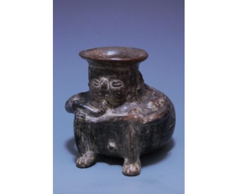 The unusual, black ware male shaman with hunchback characteristics, seated in a hunkered position, his bloated body with ribs
