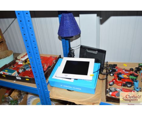 A digital clock together with a ipod dock and table lamp