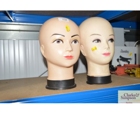 Two hairdressers practice mannequin heads