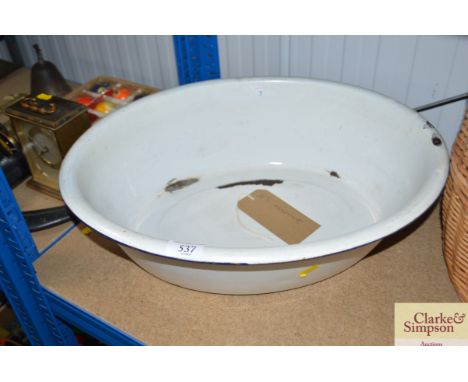 A vintage oval enamel child's bath with flanged edge and wall hanger